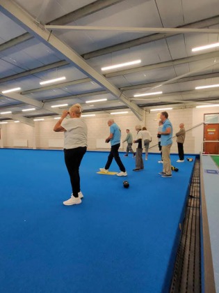 Bats Pat, John T and Russ on the indoor bowls carpet taking their turns throwing their lawn bowls